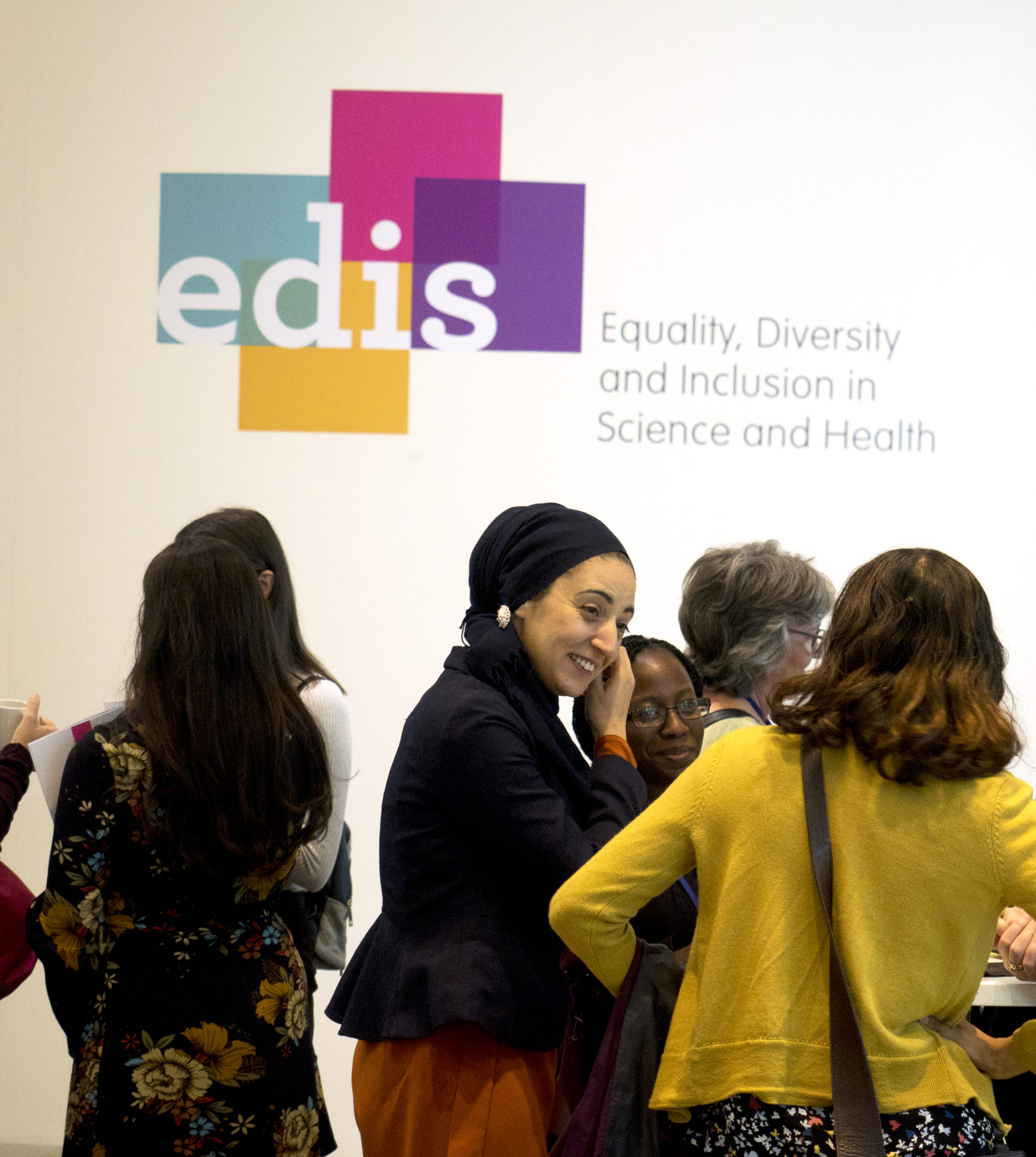 Photo of people talking and smiling underneath an EDIS wall logo